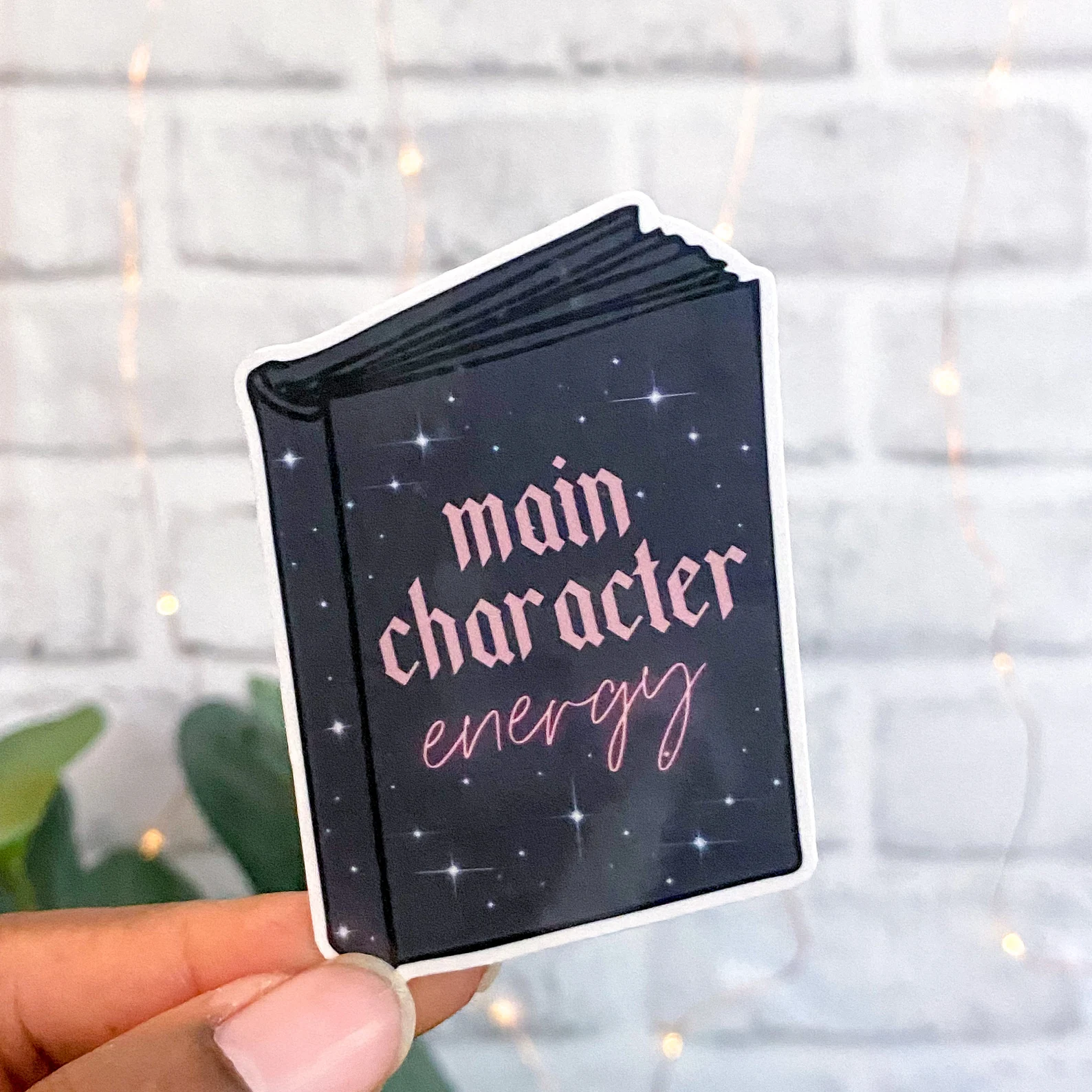 Image of a black book sticker with pink text that says "main character energy."
