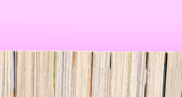 a photo of a bookshelf of manga from behind with a pink background