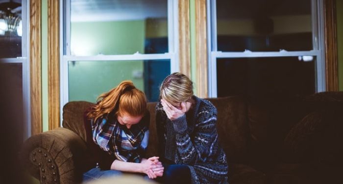 two light-skinned people with their heads down