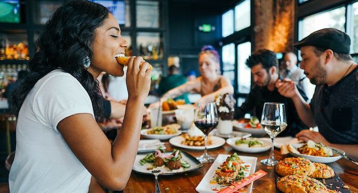 a photo of a woman smiling while eating something at a restaurant