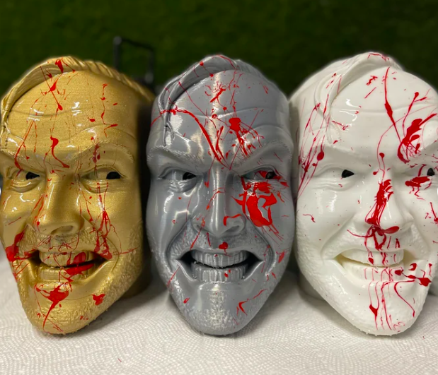 Three blood-spattered bookends that look like Jack Nicholson in The Shining. One is gold, one silver, and one white.