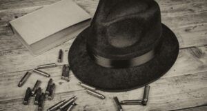 hat on a table next to bullets and a book; black and white