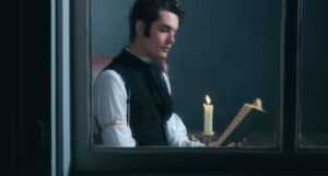 lighter-skinned man reading a book by a candle, in Victorian dress