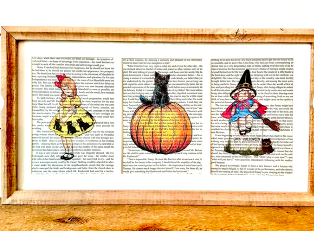 Framed book pages with colorful vintage Halloween prints on them, including a girl in a black cat dress, a black kitten atop a pumpkin, and a baby witch on a broom