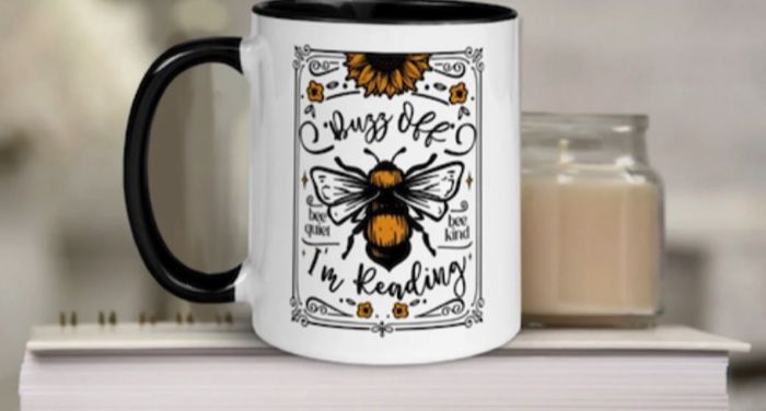 white mug black handle with illustration of bee that says buzz off I'm reading