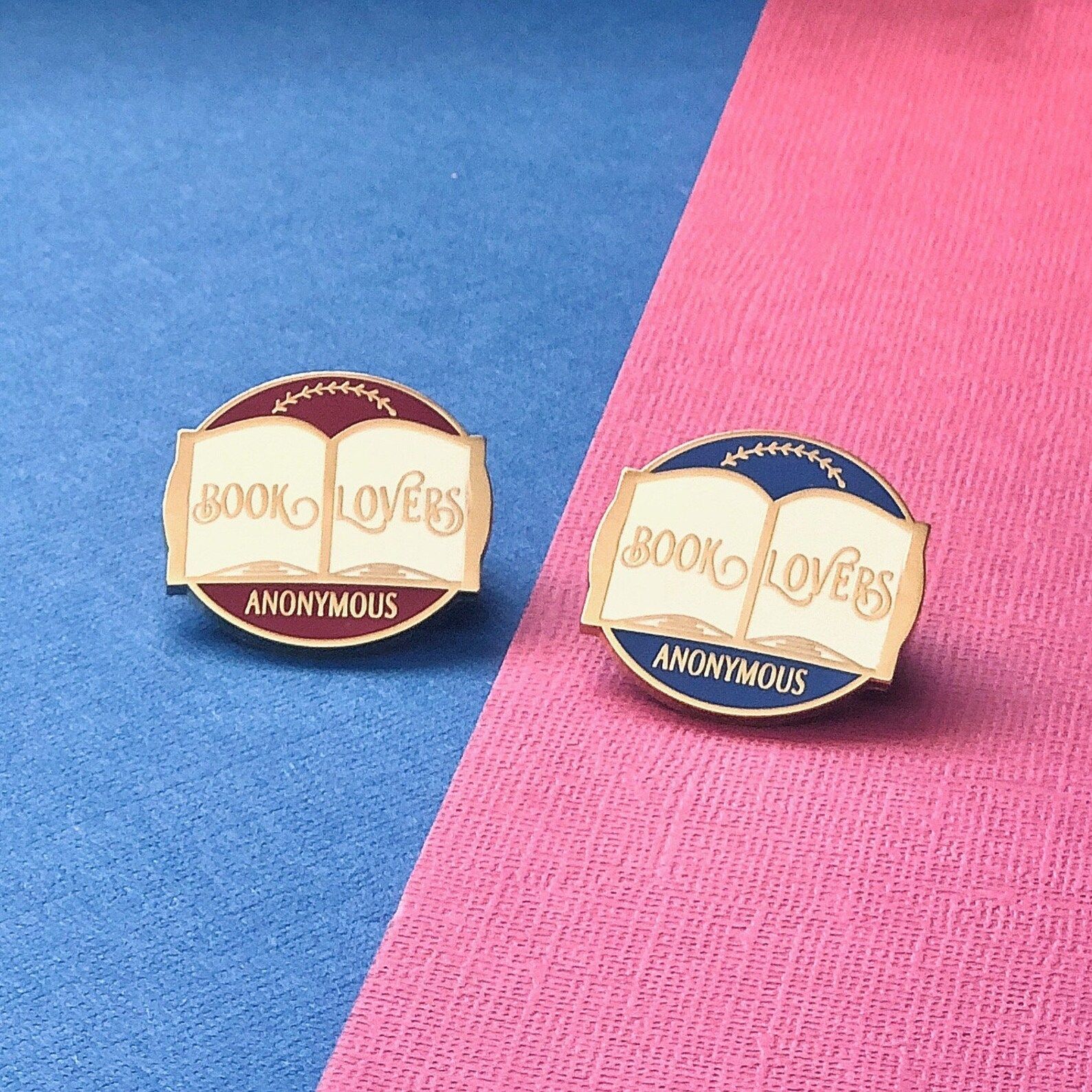 enamel pins featuring an open book that read "book lovers anonymous"