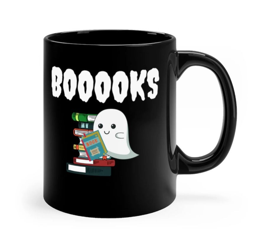 Image of a black mug with a ghost on it. The ghost is reading a book, and in white text above the image is the word 