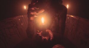 一个脖子以下涂着黑色指甲的人坐在一个血淋淋的浴缸里，手里拿着一支点燃的蜡烛
