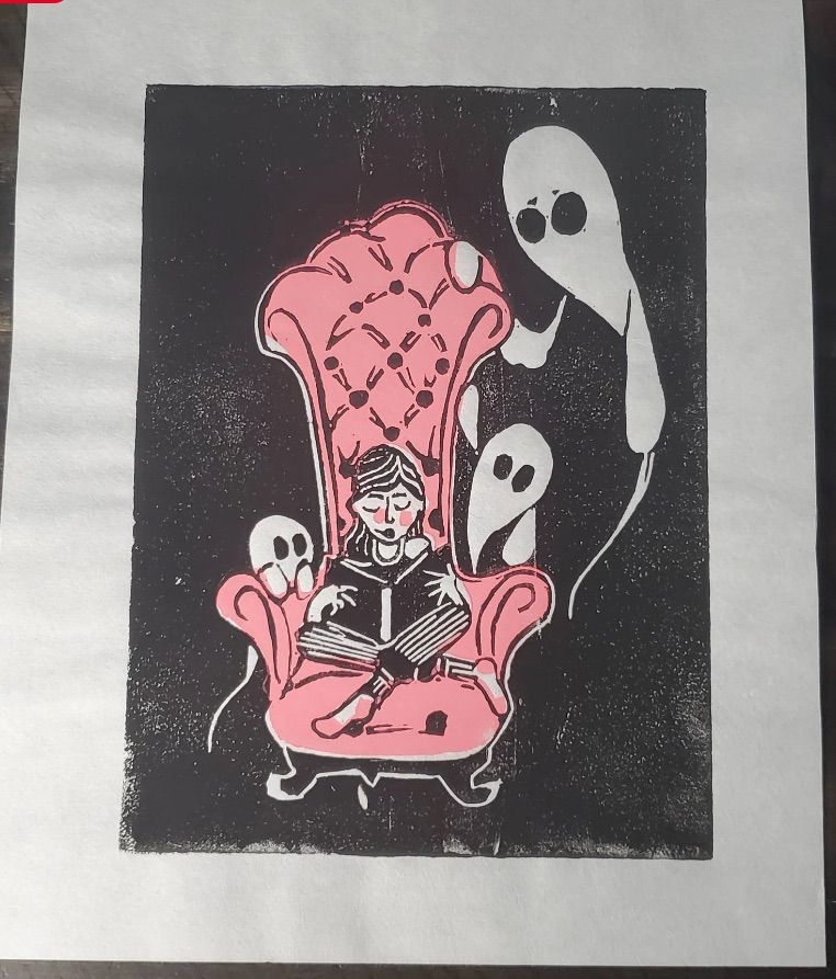Image of a person reading in a pink chair. There are ghosts surrounding it. 