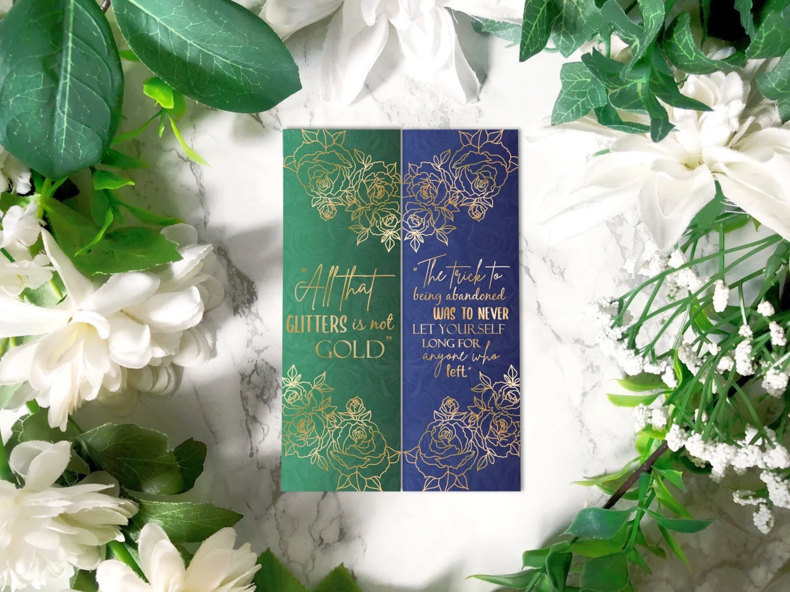 Two bookmarks, one green and one blue, with gold lead designs that showcase quotes from the books.