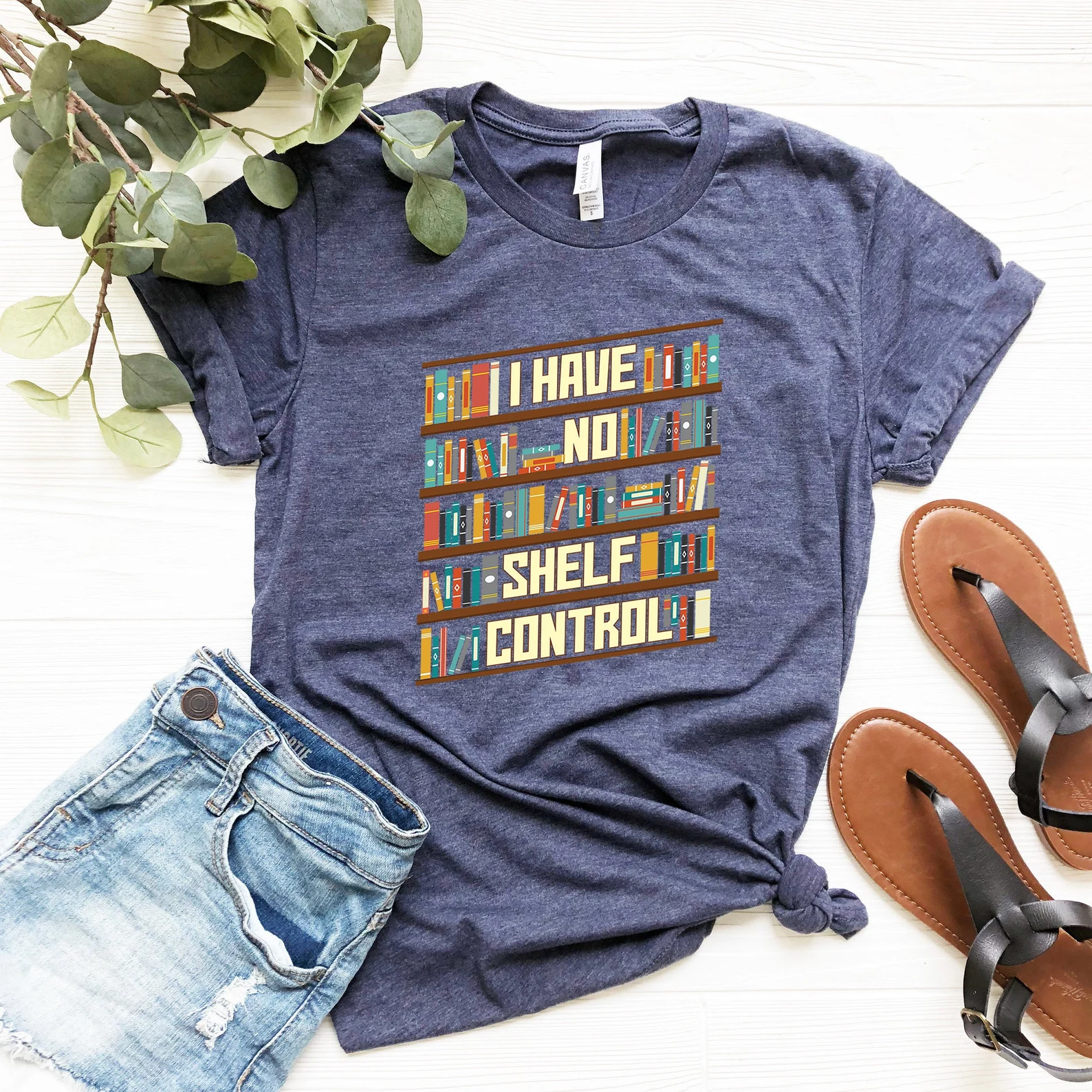 Faded blue t-shirt with colorful bookshelves and the words "I have no shelf control"