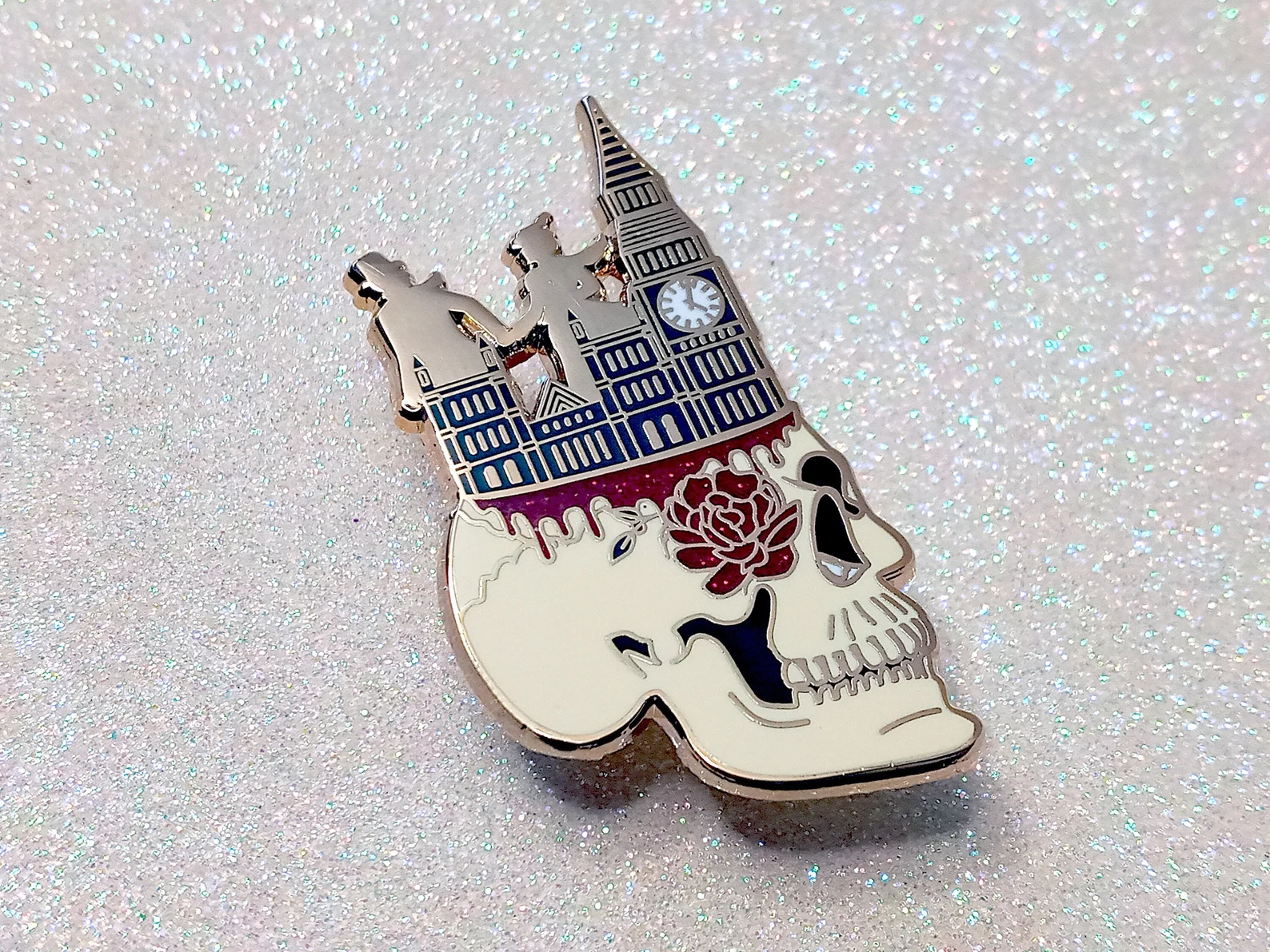 An enamel pin in the shape of a skull with Big Ben and two figures running