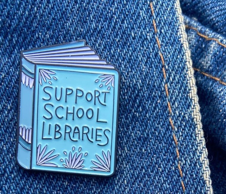 Image of a blue book-shaped pin that says "support school libraries."