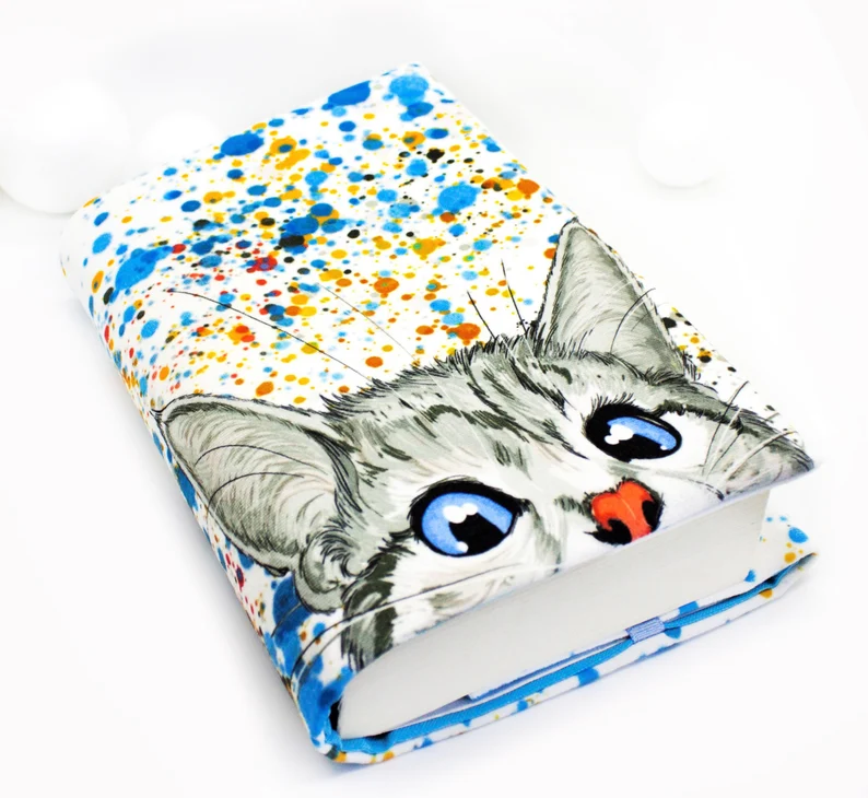 Photo of a colourful book sleeve with a print of a grey cat with beautiful blue eyes and red nose