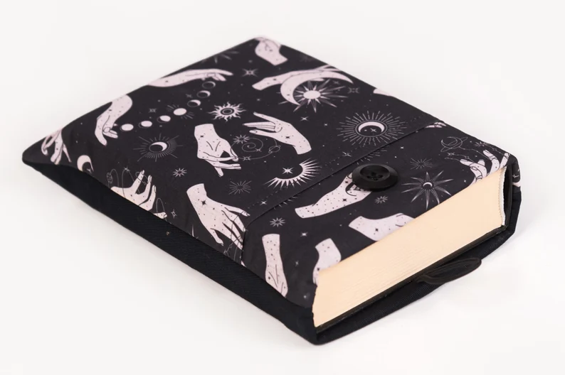 Photo of a black book sleeve with a print of hands and eyes and stars