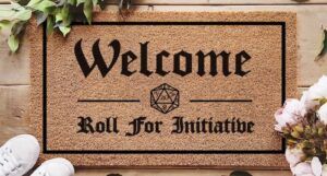 a doormat with a D20 printed on it and the text Welcome. Roll for initiative.