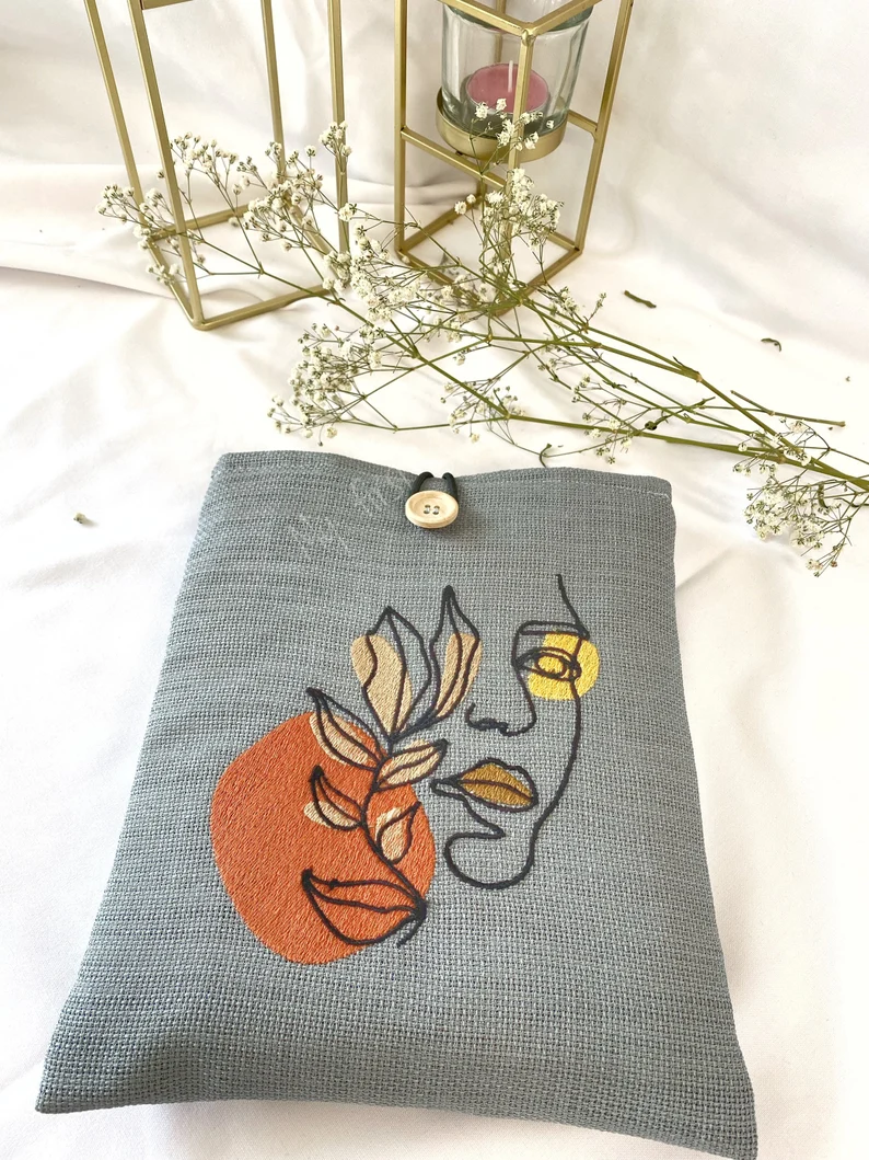 Photo of a grey book sleeve with a print of a face and lips and some leaves