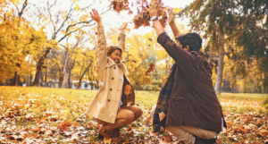 a photo of a couple throwing fall leaves in the air and laughing