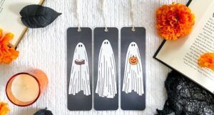 Set of three bookmarks depicting sheet ghosts, one holding a book and another holding a pumpkin