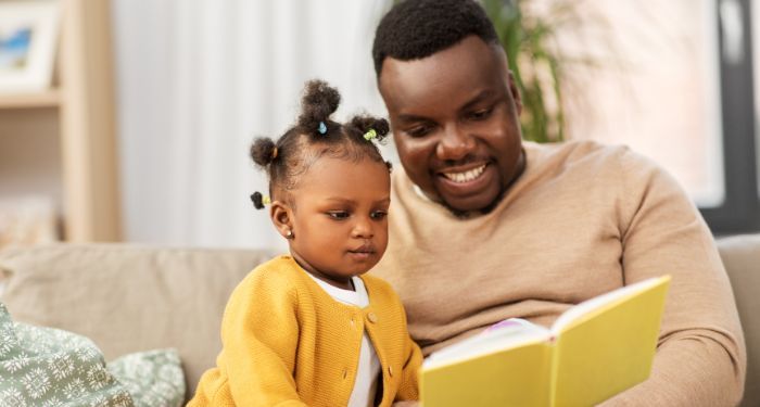 Image of a Black man reading to a child