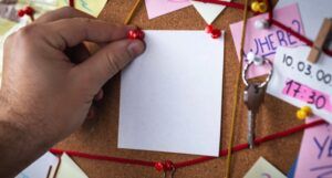 Close-up view of a detective board with evidence. In the center is a empty mock up white sheet attached with a red pin