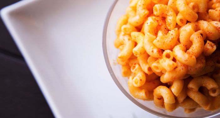 macaroni and cheese in a clear glass brown on a square white plate