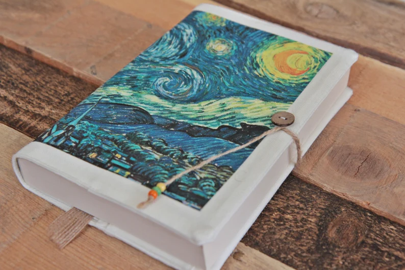 Photo of a white book sleeve on a book showing the painting Starry Night tied together with a button