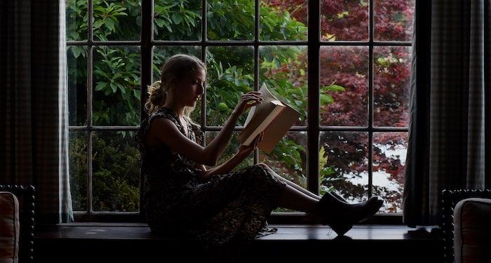 a photo of a woman reading in a window