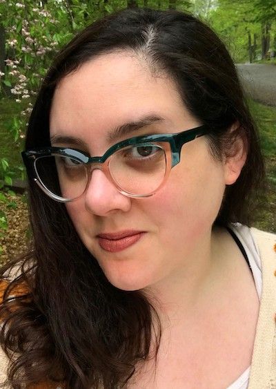 headshot of author Rev DeStefano, a brunette whir white skin wearing glasses