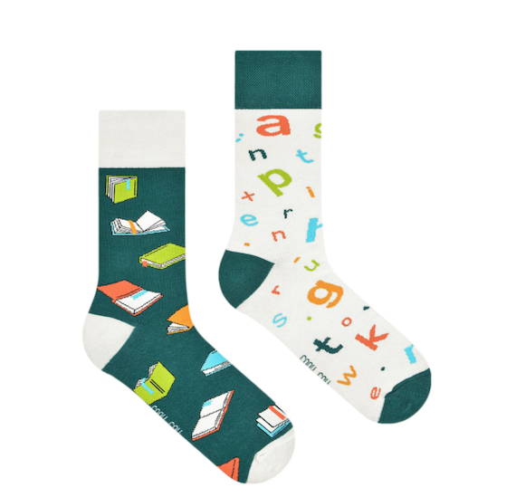 Mismatched green and white socks featuring books on one sock and letters on the other. 