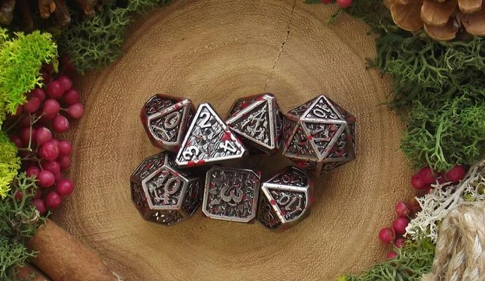 Image of metal dnd dice set with images of armour and standard weapons on each panel and small blood splatter