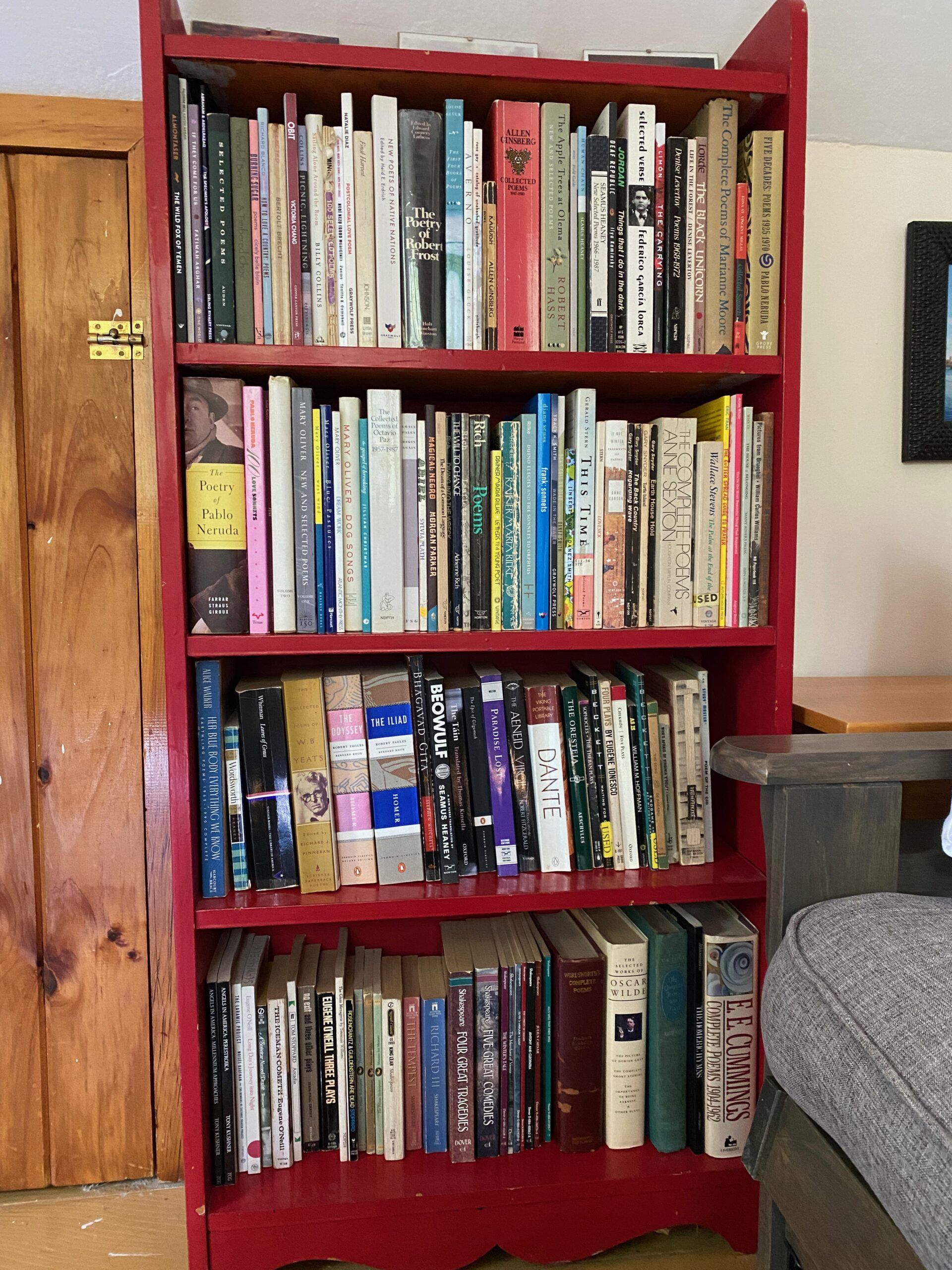 A red bookshelf full of books, mostly poetry and plays. 