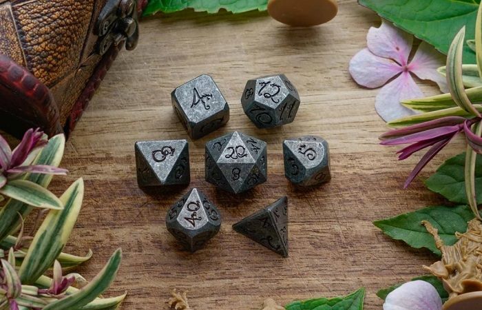 Image of metal dnd dice with a stone finish and numbers with a slight dragon look to script