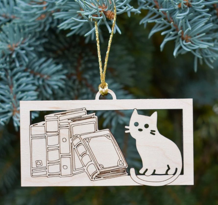 Image of an ornament featuring a cat and several books. 