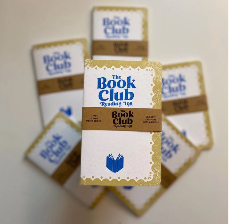 Image of a stack of small notebooks which say "the book club reading log" on them. 
