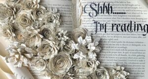 An old book opened to a sculpture of florals made of old pages.