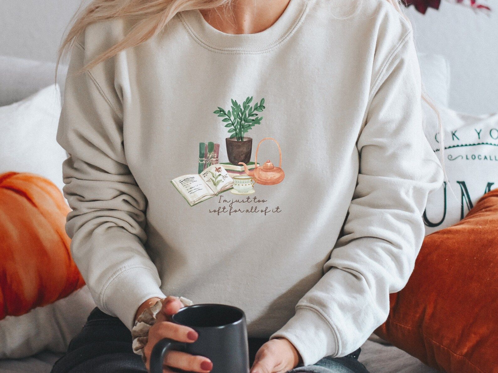 a sweatshirt with books, tea kettle, and plants on it that reads "I'm just too soft for all of it"