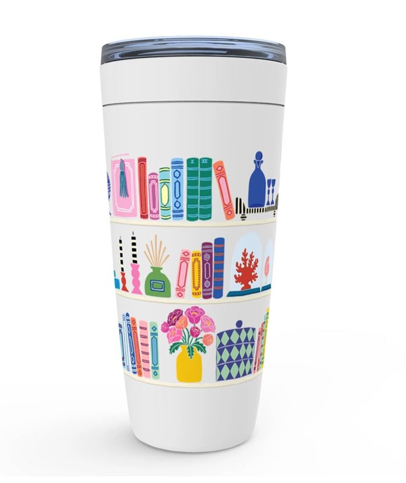 White tumbler with colorful books anad flowers on it. 
