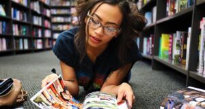 tan-skinned girl reading comics on the floor