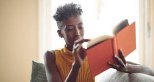 Image of a Black person reading an orange book