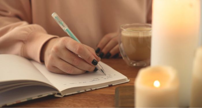 Image of a person with light skin writing in a journal