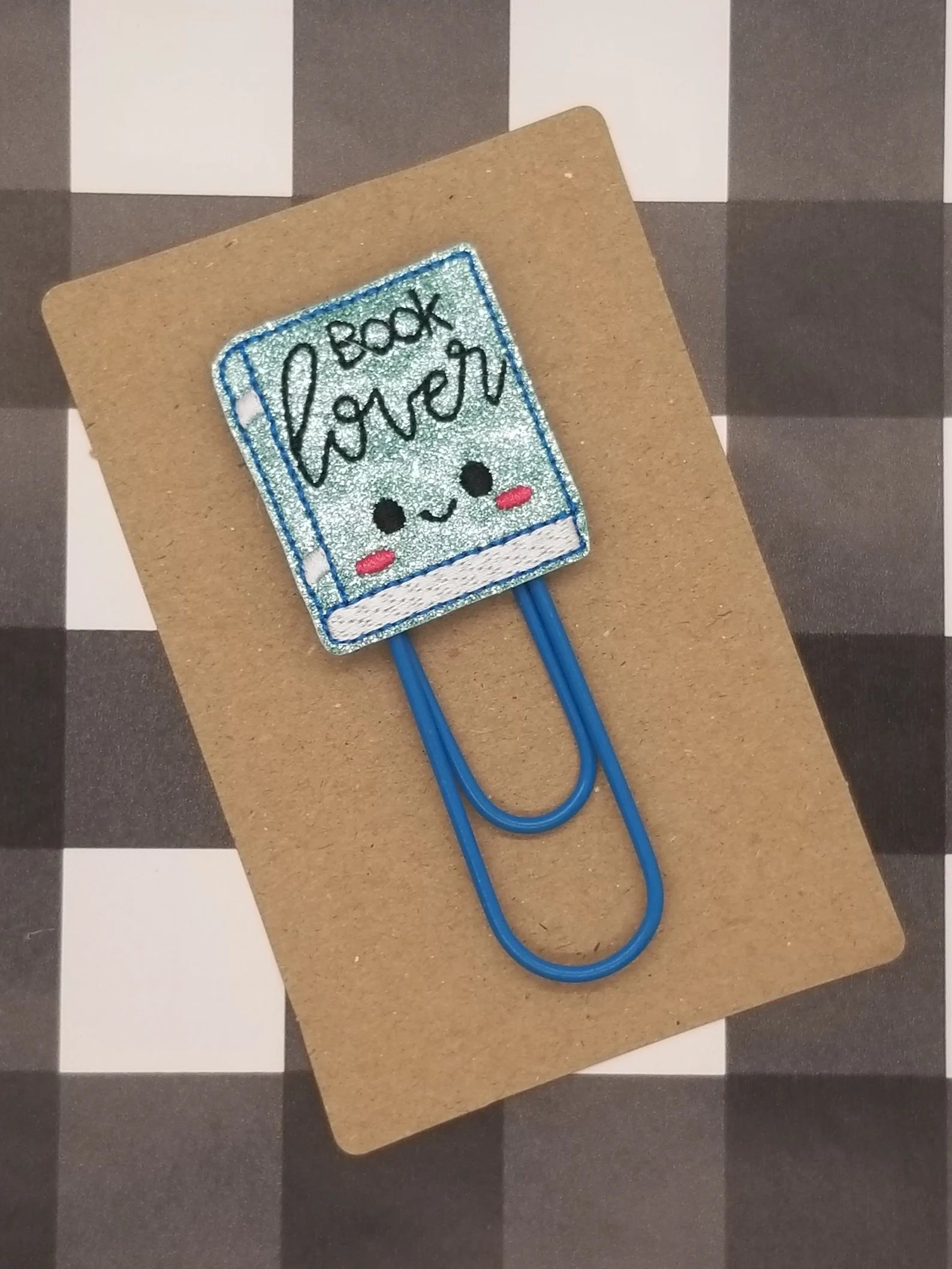 paper clip with a kawaii smiley faced book saying "book lover"