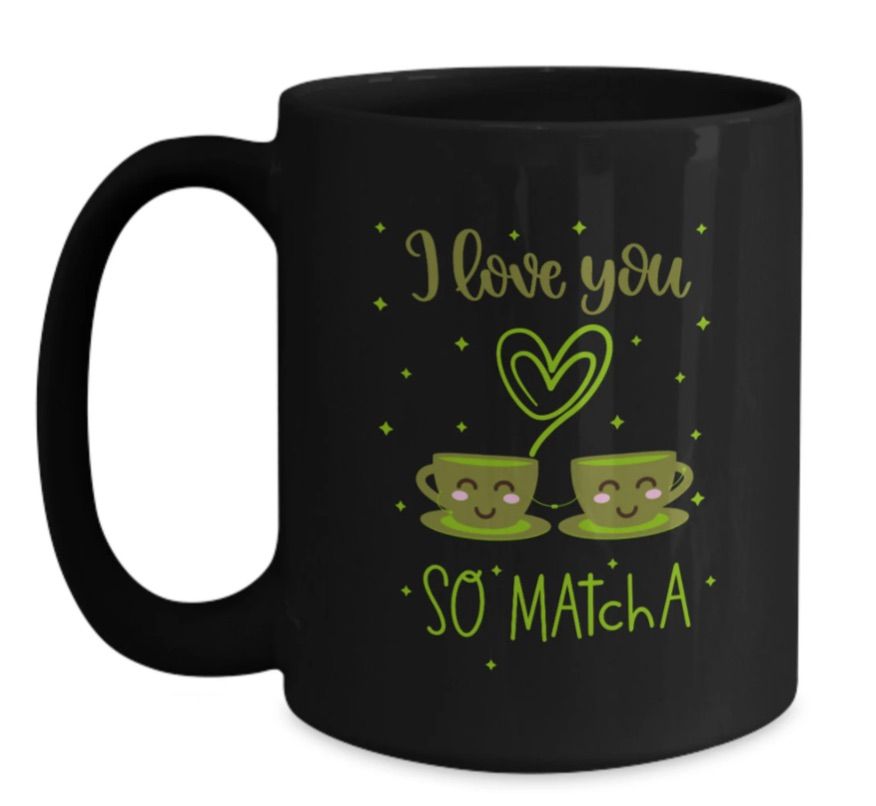 Image of a black mug. It has green text that says "I love you so matcha," with an image of two cups of matcha underneath a heart. 