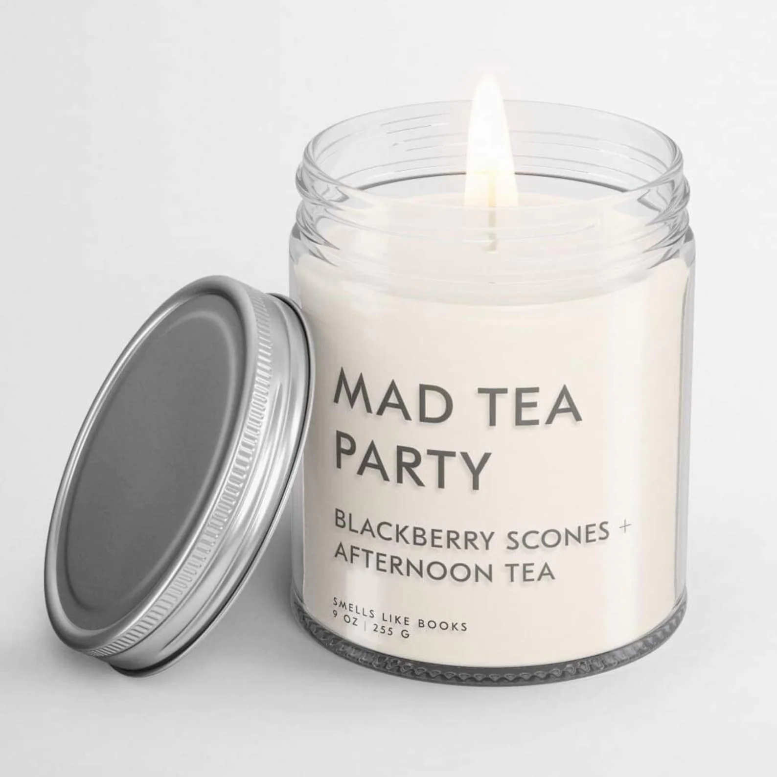 a white candle with a jar lid that reads "Mad Tea Party"