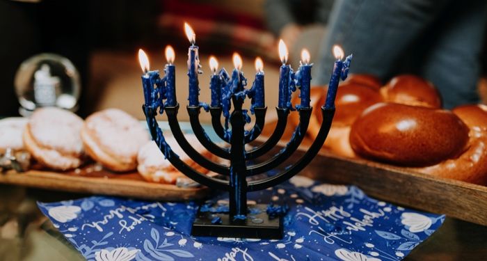 a menorah with blue lit candles that are mostly melted down with plates of breads and sweets in the background