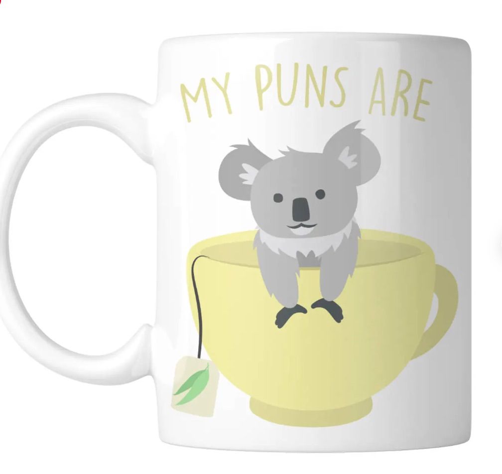 Image of a white mug. In yellow letters it says "my puns are" and below it is an image of a koala inside a tea cup. 