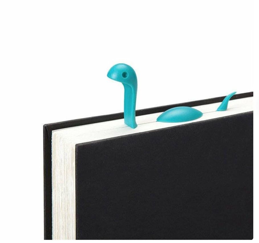 Image of a blue bookmark poking out of the top of a book. It looks like nessie the sea monster. 