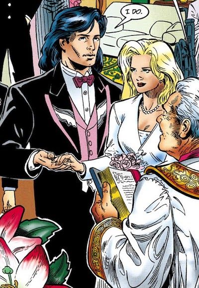 Part of a page from Nightwing Annual #1. Dick is wearing a black tux with light pink trim, a light pink vest, and a darker pink bow tie. His bride, a blonde woman, is wearing a white suit. They look unenthused.