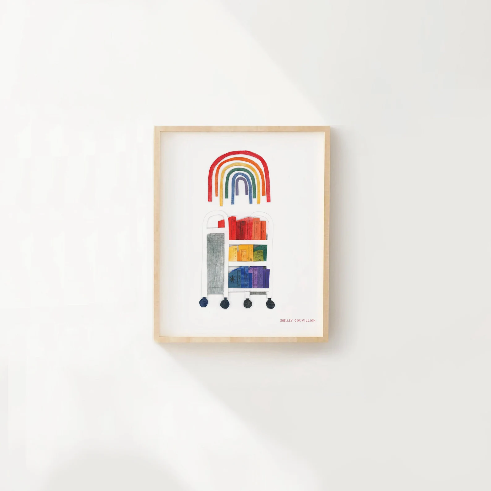 a framed print of a book cart holding a rainbow of books