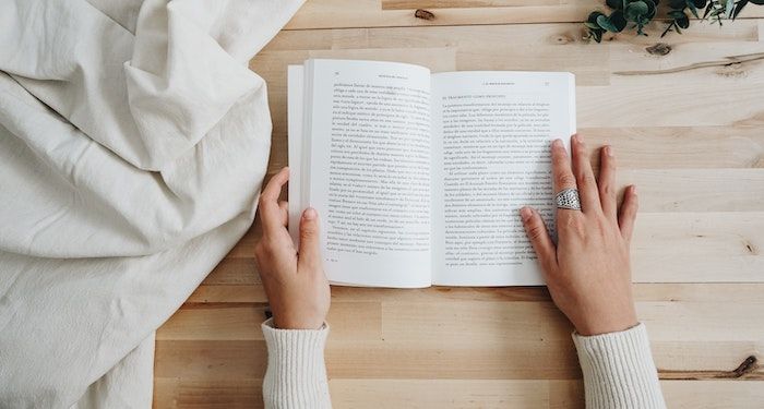 a photo of someone's hands as they are reading a book that is on a table